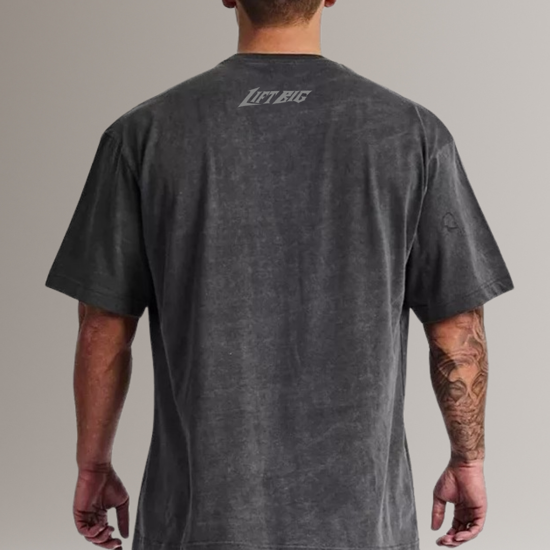 Person wearing a dark gray t-shirt with 'Lift Big' text on the back, standing against a plain background.