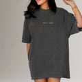 Woman wearing oversized black t-shirt with 'SELF LOVE' text, fitness apparel style.