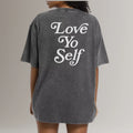 Woman wearing oversized black fitness t-shirt with 'Love Yo Self' printed on back