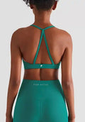Woman wearing teal strappy sports bra and high-waisted leggings, back view