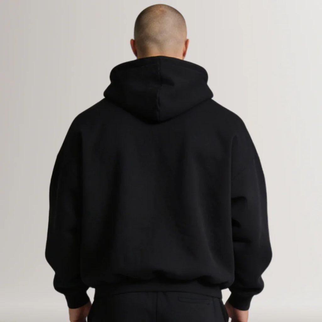 Person wearing a black hoodie from behind on a plain background