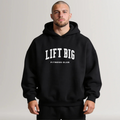 Man wearing a black hoodie with 'LIFT BIG Fitness Club' text on a plain background