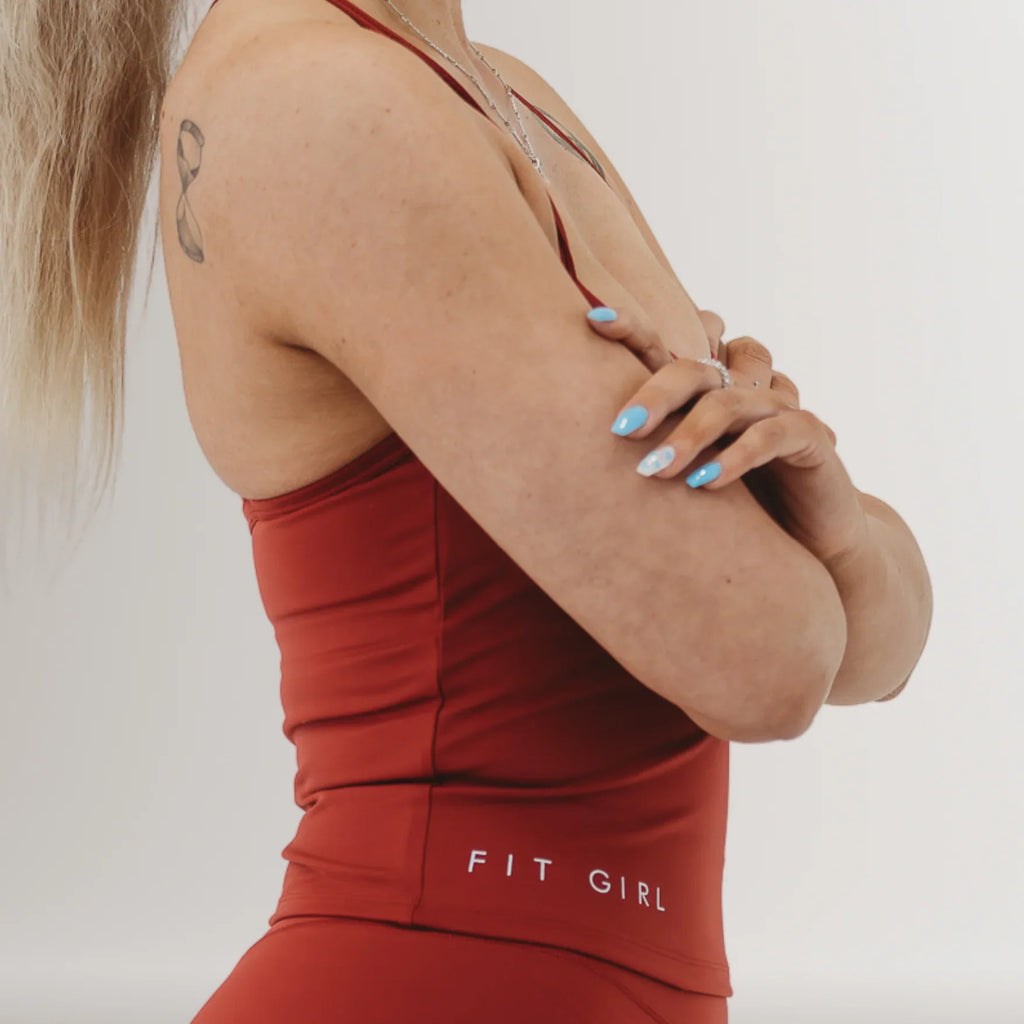 Woman in red fitness apparel with 'Fit Girl' text, showing activewear and tattoo
