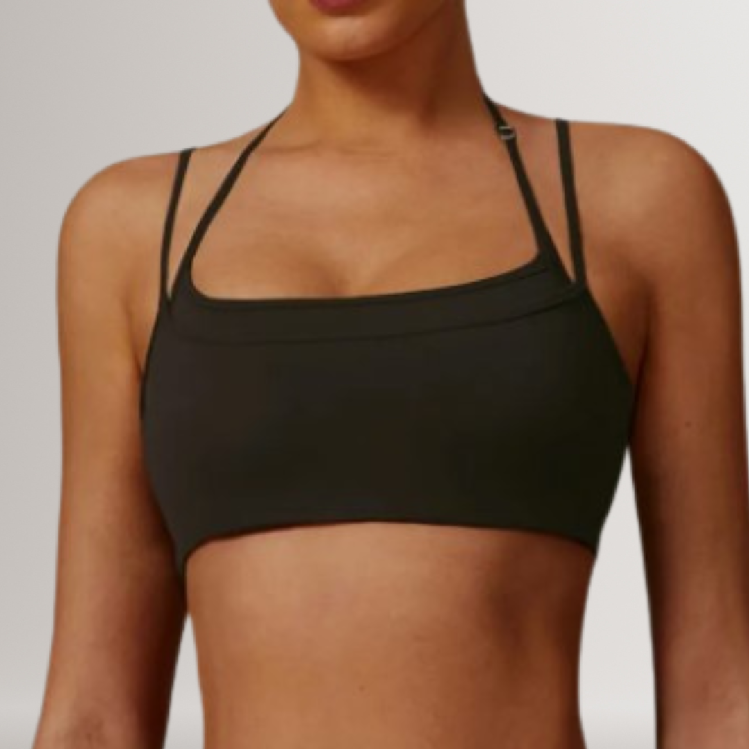 A black sports bra with a straight neckline and adjustable straps, shown on a model.