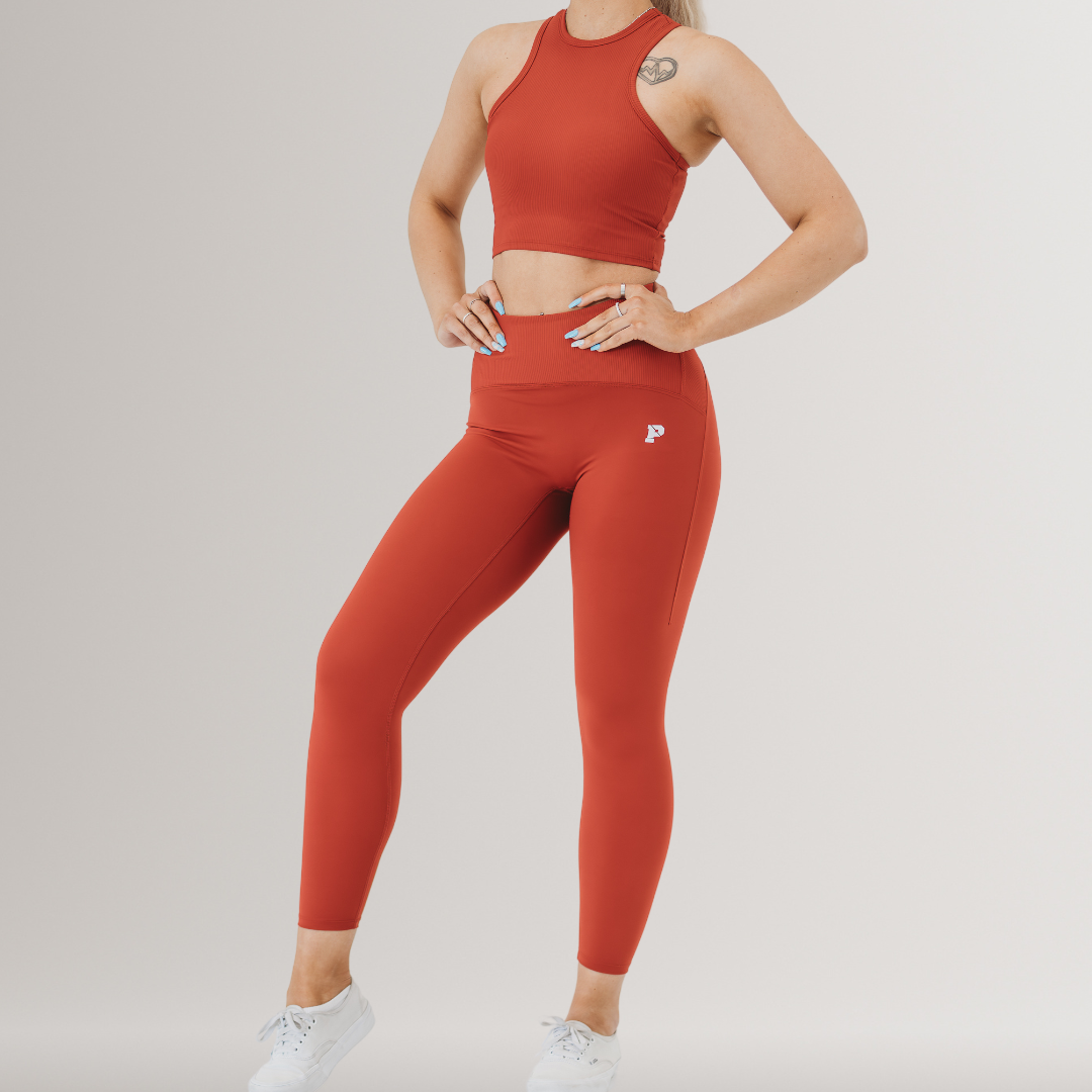 A woman wearing a matching set of deep red legging and sports crop top.