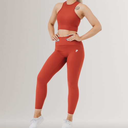 A woman wearing a matching set of deep red legging and sports crop top.
