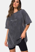 Woman wearing oversized stone washed SELF LOVE graphic t-shirt and black workout shorts